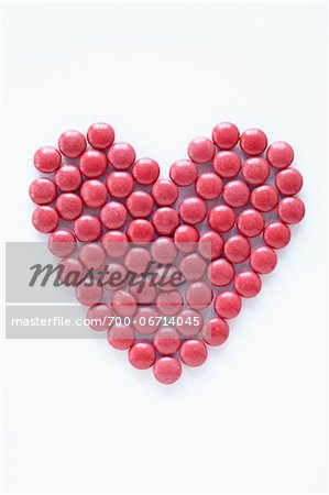 close-up of red pills arranged into heart shape on white background