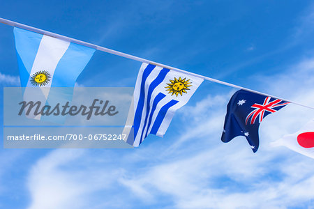 Uruguayan, Argentinian, Australian, and Japanese flags against blue summer sky