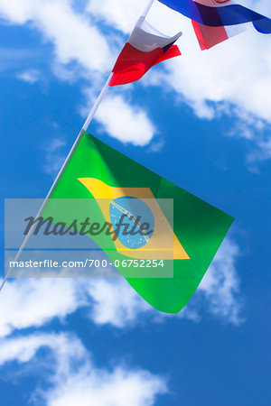 Brazilian and French flags against blue summer sky
