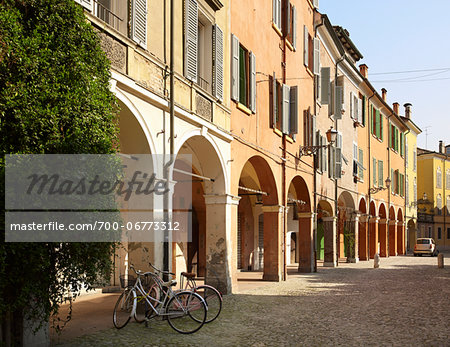 bicycles parked on cobblestone street, beside quaint buildings with window shutters, and archways, Modena, Italy bicycles parked on cobblestone street, beside quaint buildings with window shutters, and archways, Modena, Italy