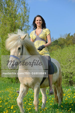 Young woman riding an icelandic horse on a meadow in spring, Germany
