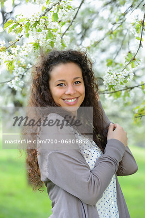 Close-up of a young woman standing beside a flowering cherry tree in spring, Germany