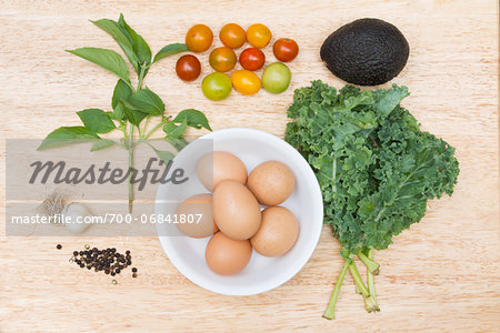 Overhead view of fresh local organic ingredients: eggs, cherry tomato, avacado, garlic, lemon basil, pepper and kale; jeffersonville, georgia