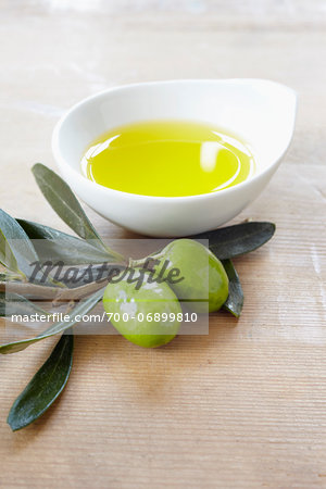 close-up of small bowl with olive oil, olive twig and fresh olives