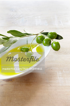 close-up of small bowl with olive oil, olive twig and fresh olives close-up of small bowl with olive oil, olive twig and fresh olives