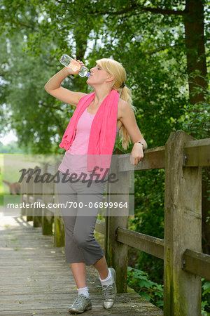 Blond athletic woman drinking from water bottle outdoors, Germany