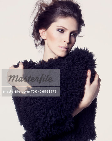 Portrait of woman wearing black, knitted top, studio shot on white background