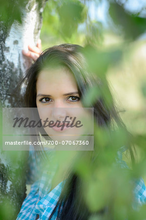 Close-up portrait of young woman standing beside tree, Bavaria, Germany