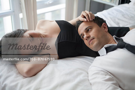 Couple laying on bed in formal wear, looking at each other