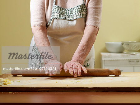 Elderly Italian woman making pasta by hand in kitchen, rolling dough, Ontario, Canada
