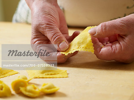 Close-up of elderly Italian woman's hands shaping ravioli pasta dough in kitchen, Ontario, Canada