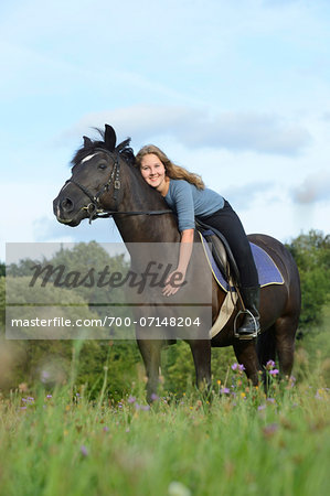 Teenage girl standing next to a Arabo-Haflinger horse in meadow, Bavaria, Germany