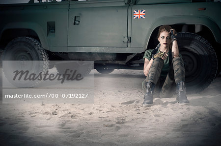 Woman Soldier Sitting on Ground by Military Vehicle Woman Soldier Sitting on Ground by Military Vehicle