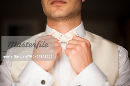 Close-up of Groom adjusting bow tie and getting ready on Wedding Day, Canada