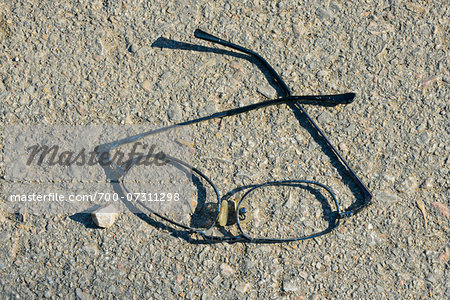 Close-up of broken eye glasses on pavement