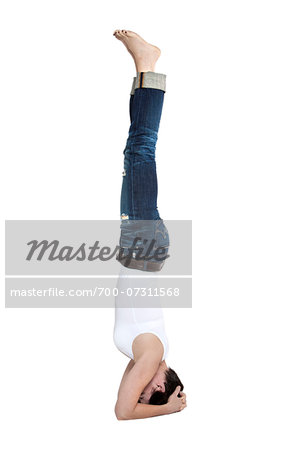 Woman in headstand yoga position in the forearm balance pose, studio shot on white background