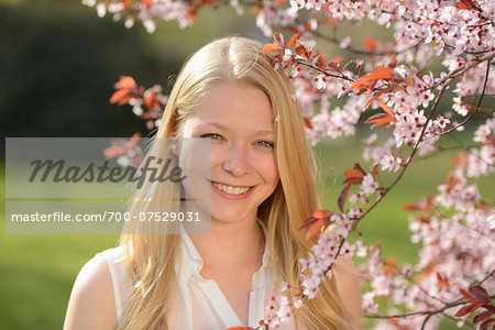 Portrait of Young Woman by Cherry Plum Tree Blossoming in Park in Spring, Franconia, Bavaria, Germany