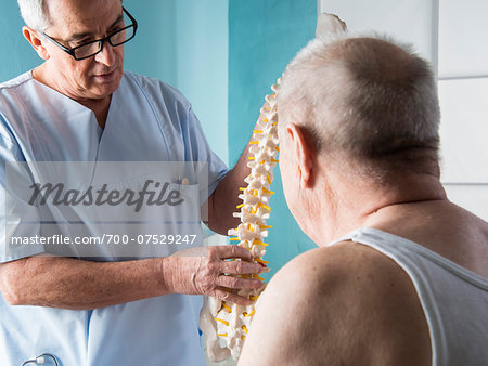 Senior, male doctor discussin spinal cord with senior, male patient, in office, Germany