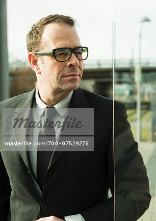 Portrait of businessman wearing glasses, standing at train station outdoors, Mannheim, Germany