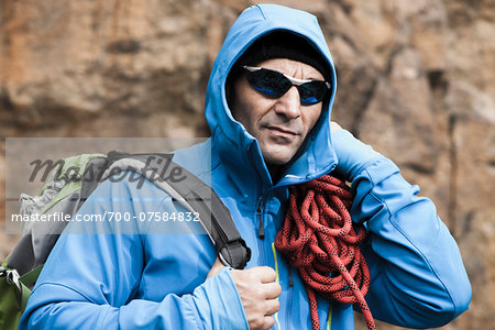 Close-up portrait of man wearing jacket and sunglasses carrying rock climbing gear, Germany