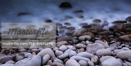 Close-up of shoreline with boulders and incoming tide, long exposure, Scotland.