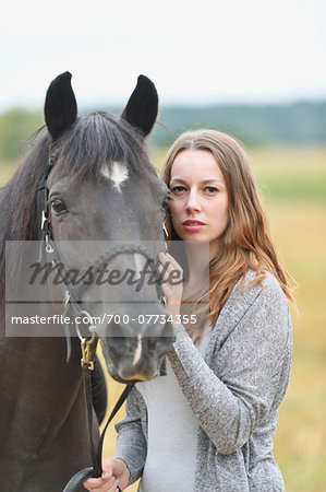 Close-up portrait of a young woman with an Arab-Haflinger horse on a field in summer, Upper Palatinate, Bavaria, Germany