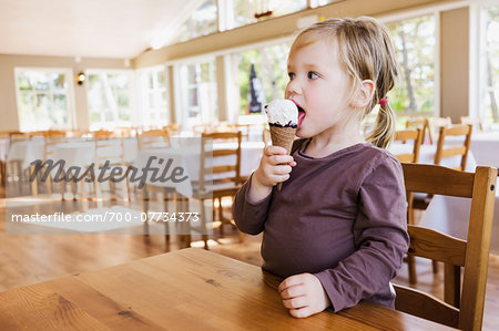 2 years old girl eating an ice cream in a restaurant dining room, Sweden