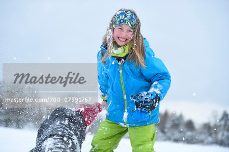 Close-up of two girls playing in the snow havng a snowball fight, winter, Bavaria, Germany