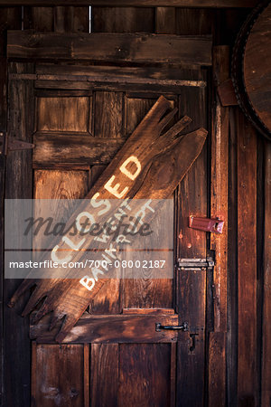 Close-up of old, wooden door with 'bankrupt' sign