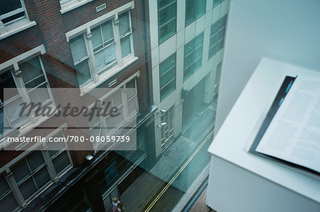 High angle view of street and office building from desk window with reflection on glass, London, England