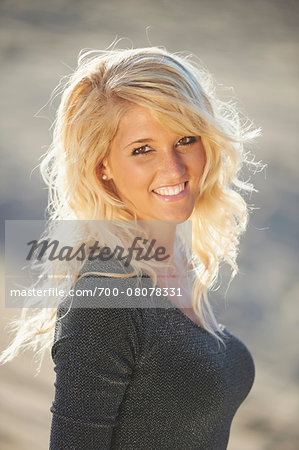 Portrait Of Young Woman With Blond Hair On Sandy Beach In Summer