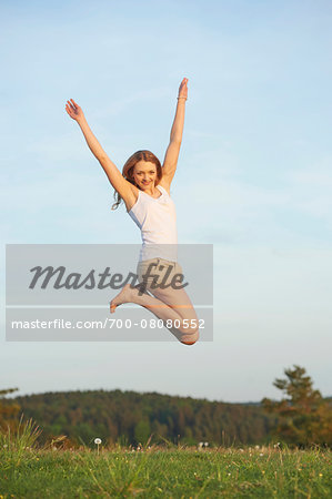 Young woman jumping in the air on a meadow in spring, Germany