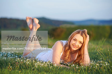 Young woman lying on grass in a meadow at sunset in spring, Germany Young woman lying on grass in a meadow at sunset in spring, Germany