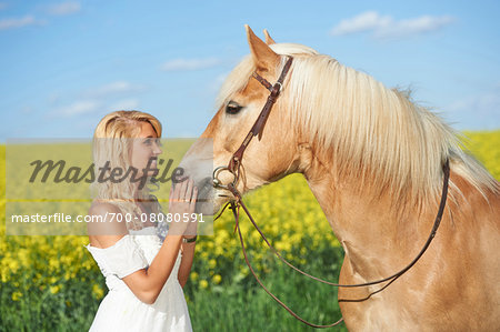 Young woman standing beside a haflinger horse in spring, Bavaria, Germany Young woman standing beside a haflinger horse in spring, Bavaria, Germany