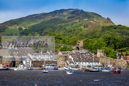 Riverfront view showing walled city of Conwy with boats in harbour, Conwy County, Wales, United Kingdom