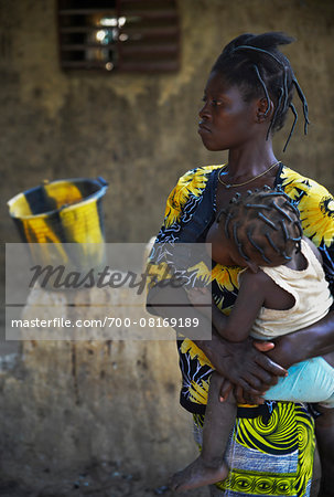 Mother holding child in arms while nursing, black and yellow patterns, Gaoua, Poni Province, Burkina Faso