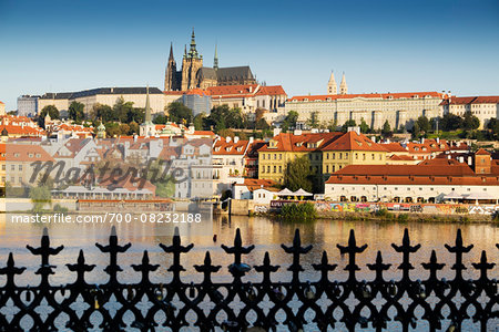 Wrought iron fence and harbor scene with St Vitus Cathedral in background at sunset, Prague, Czech Republic