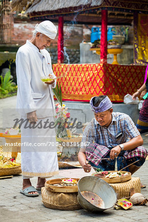 Hindu priest watches man light incense at a Bulan Pitung Dina (One Month and One Week) purification ceremony for baby and parents, Ubud, Bali, Indonesia