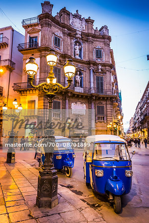 Parked scooter taxis under lamp post at the West building at Piazza Vigliena (Quattro Canti) on Corso Vittorio Emanuele at dusk in Palermo in Sicily, Italy