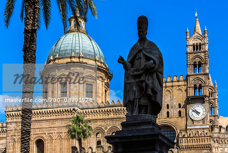 Silhouetted statue of Archbishop in front of the dome and clock tower of the Palermo Cathedral in historic Palermo in Sicily, Italy