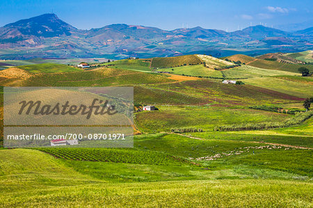 Scenic vista of farmland dotted with buildings with mountain range in the background near Calatafimi-Segesta in the Province of Trapani in Sicily, Italy