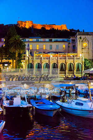 Boats docked at marina with the Venetian Loggia and the Hvar Fortress overlooking the harbour at night in the Old Town of Hvar on Hvar Island, Croatia