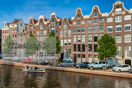 Typical buildings and cars parked along the seawall of the Prinsengracht canal in Amsterdam, Holland