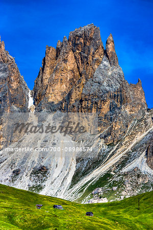 Grassy mountain side at the Sella Pass with the jagged mountain tops of the Dolomites in South Tyrol, Italy