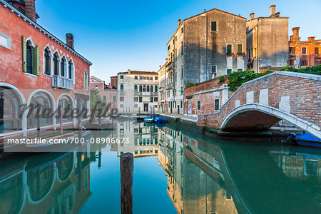 Reflection of the historic buildings in the Rio de Malcanton canal at sunrise with Ponte Marcello on the right in Venice, Italy