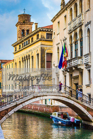 Stone footbridge with iron railing crossing a canal in Venice, Italy
