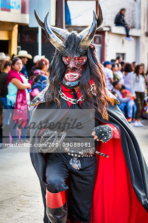 Close-up an indigenous tribal dancer wearing a black and red costune with mask and horns in the St Michael Archangel Festival parade in San Miguel de Allende, Mexico