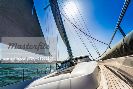 Backlit sails of sailboat in the Sydney Harbour with the Sydney Harbour Bridge in the background in Sydney, New South Wales, Australia