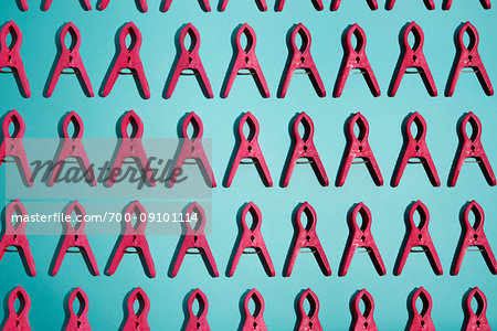 Repetitive red clips in rows on a turquoise background