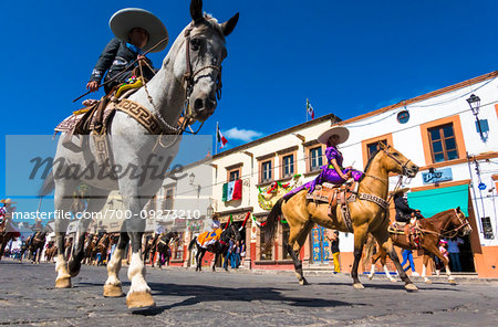 Horseback riders in traditional costums on cobblestone street at the Mexican Independence Day Parade in San Miguel de Allende, Guanajuato, Mexico